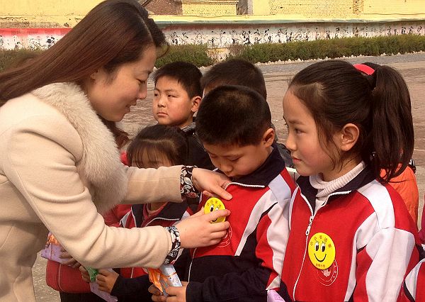图为周楼小学校长吴海燕为评选出的“小小书法家”佩戴奖章。