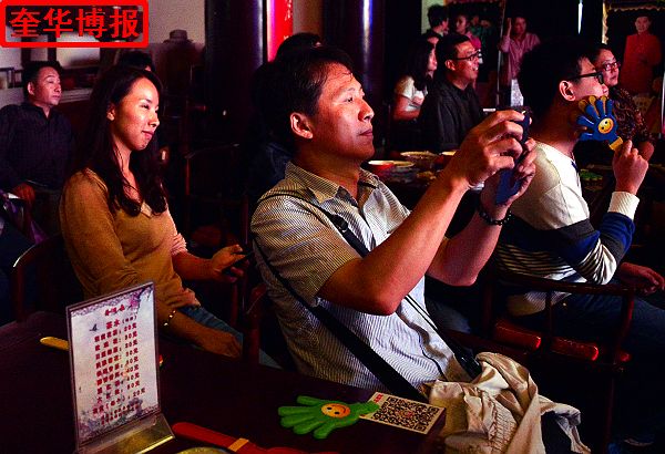 2014年9月20日，在山东济南明湖居开心剧场台湾客商林先生一边观看节目、一边拍照。