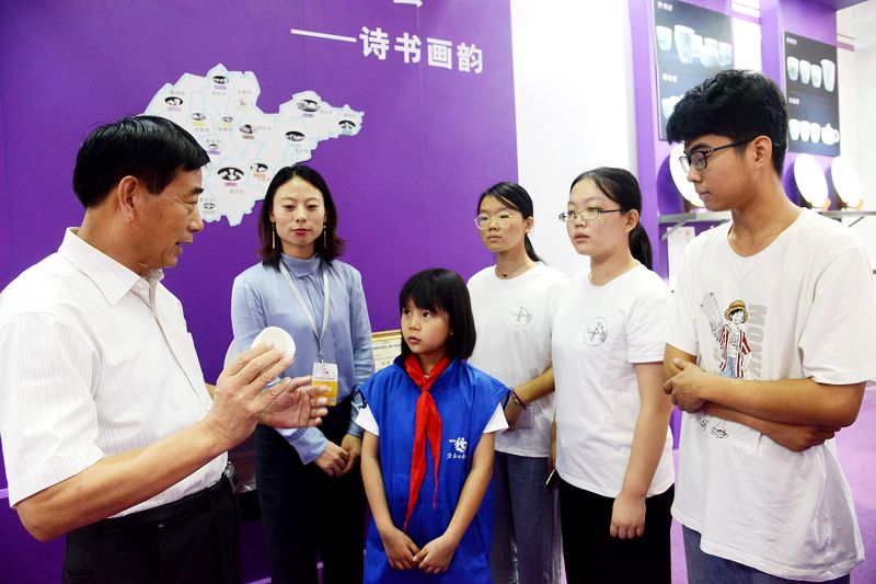 2019年9月22日，李新华（左一）在第八届山东国际文化产业交易博览会展馆向客人介绍德化.jpg